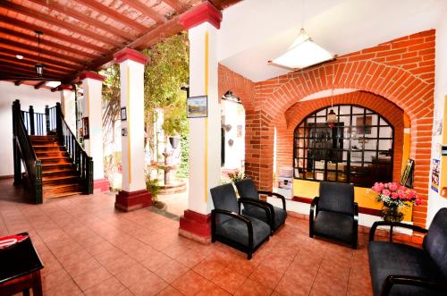 a lobby with black chairs and a brick wall at Hostal Riviera Sucre in Otavalo