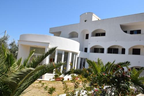 a white building with palm trees in front of it at Hotel Maggiore in Vieste