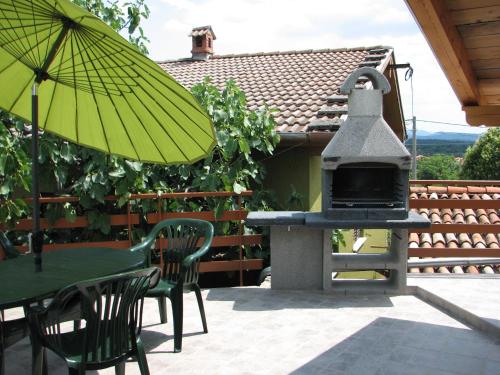 a patio with a grill and a table and chairs with an umbrella at Apartma Furlan in Štanjel