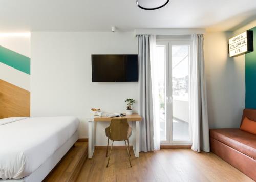 a hotel room with a bed and a desk and a window at Colors Urban Hotel Thessaloniki in Thessaloniki