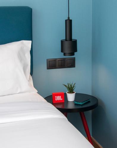 a bedroom with a bed and a table with a clock at Colors Urban Hotel Thessaloniki in Thessaloniki