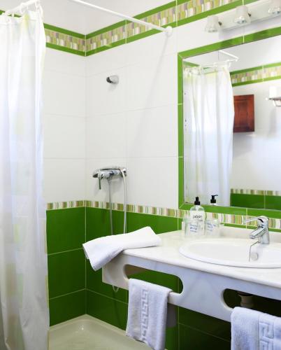 a green and white bathroom with a sink and a mirror at Hospedería Santiago in Chiclana de la Frontera