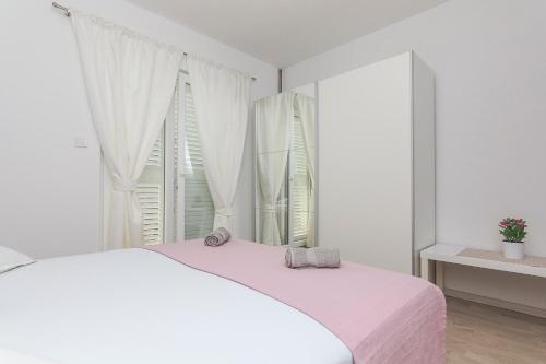 ein weißes Schlafzimmer mit einem weißen Bett und einem Fenster in der Unterkunft APARTMENTS A&B in Makarska