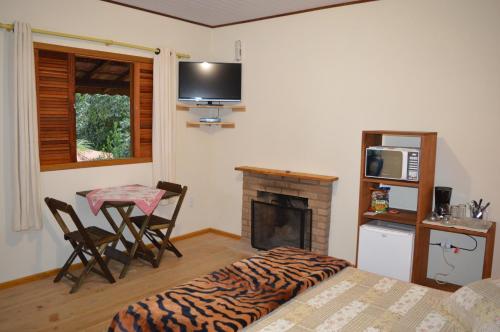 a bedroom with a bed and a table and a fireplace at Chalés do Pardal in Visconde De Maua