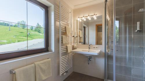 a bathroom with a sink and a shower and a window at Hotel Niederreiter in Maria Alm am Steinernen Meer