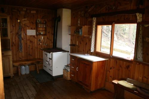a kitchen with a stove and a window in a cabin at Gästehaus Berger - Priglhof in Treffen