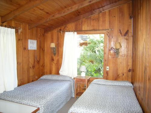 two beds in a room with a window at Cabañas Mapulay in Pucón