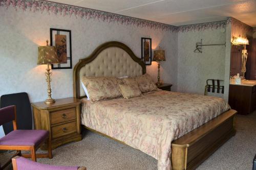 a bedroom with a large bed and a purple chair at Rivergate Mountain Lodge in Pigeon Forge