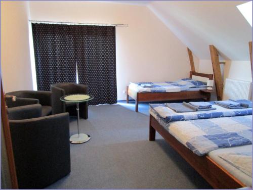 a bedroom with two beds and a chair and a table at Penzion Alma in Znojmo