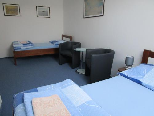 a room with two beds and a table and a couch at Penzion Alma in Znojmo