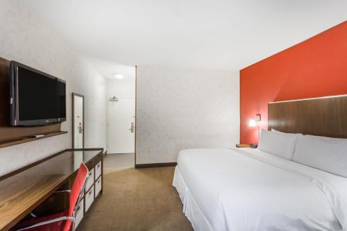 a hotel room with a large bed and a flat screen tv at La Hacienda San Jose Silicon Valley in San Jose