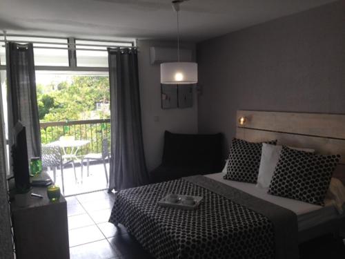 a bedroom with a bed and a view of a patio at Studio Bas du Fort Guadeloupe in Le Gosier
