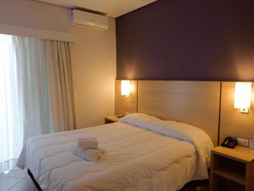 a hotel room with a large white bed with towels on it at The World Indaiatuba in Indaiatuba