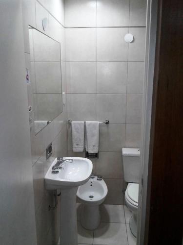 a white bathroom with a sink and a toilet at Hotel Milena in Mendoza