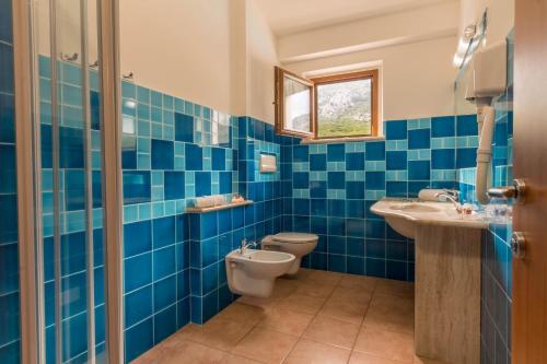 a blue tiled bathroom with a toilet and a sink at Hotel Brancamaria in Cala Gonone