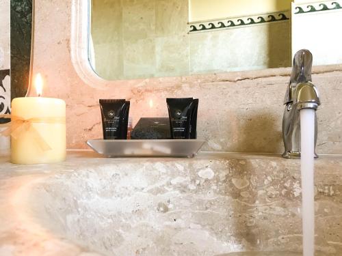 a bathroom sink with a candle and a soap dispenser at Hotel Brancamaria in Cala Gonone