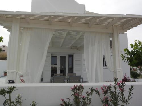 a white porch with white curtains and chairs on it at JB Villa in Mesaria