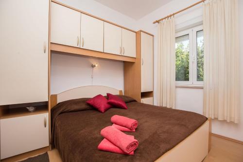 Un dormitorio con una cama con almohadas rojas. en Apartments & Rooms Tea, en Zadar