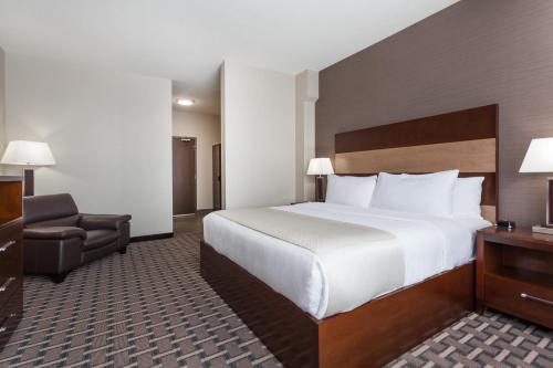 a hotel room with a large bed and a chair at Wyndham Garden Edmonton Airport in Leduc