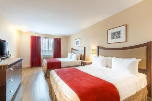 a hotel room with two beds and a flat screen tv at Hotel Ambassadeur et Suites in Quebec City