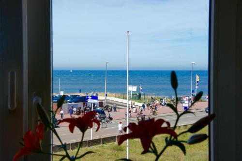 une vue de la plage depuis une fenêtre avec des gens sur la plage dans l'établissement Odyssee, à Zandvoort