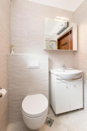 a white bathroom with a toilet and a sink at Apartment Pepi in Lovran