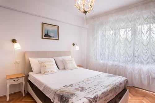 a bedroom with a bed and a window with a chandelier at Apartment Pepi in Lovran