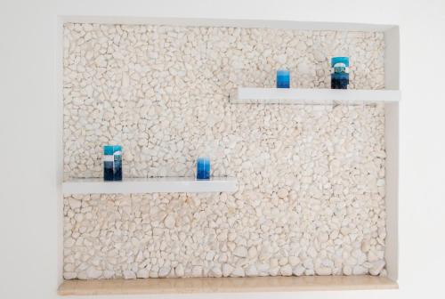 deux étagères sur un mur de pierre avec des vases bleus dans l'établissement Carpe Diem Studios, à Ialyssos