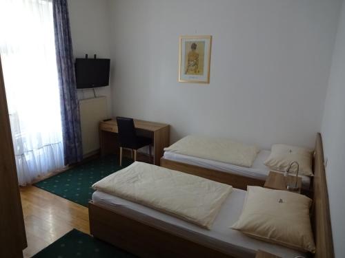 a room with two beds and a desk and a television at Hotel & Hostel Sandwirt in Bad Ischl