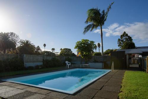 a swimming pool in the backyard of a house at Kauri Lodge Motel in Kaitaia