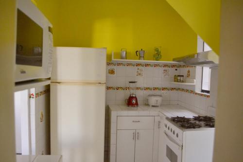 a kitchen with white appliances and a yellow wall at Casa Rodas in Lima