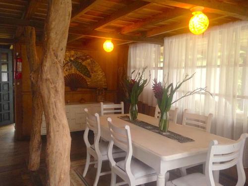 a dining room table with white chairs and flowers on it at Casa de Piedra in Mindo