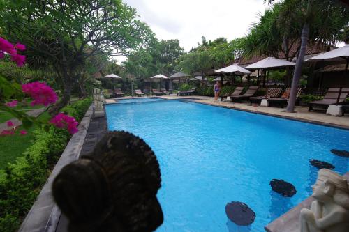 - une piscine dans un complexe avec une statue au premier plan dans l'établissement Tirta Sari Bungalow, à Pemuteran
