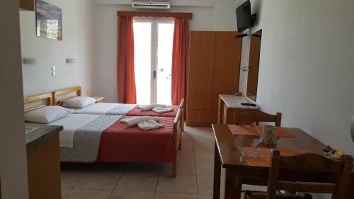 a bedroom with a bed and a table and a window at Sofia Studios & Apartments in Georgioupolis