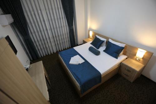 a hotel room with a bed with blue pillows at Hotel Pejton in Pristina