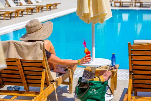 a person in a hat sitting at a table by a pool at Ada Julian Marmaris in Marmaris