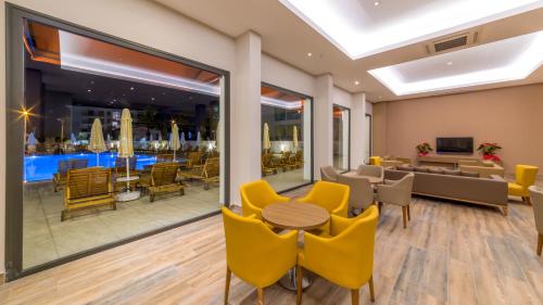 a lobby with yellow chairs and a table and a restaurant at Ada Julian Marmaris in Marmaris