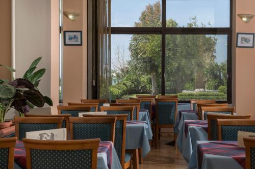 a row of tables and chairs in a room with windows at Delfini Hotel in Patra