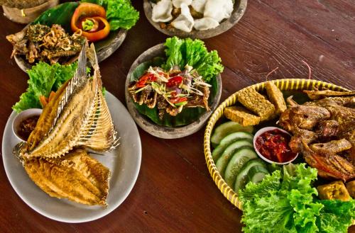 a wooden table with plates of food on it at Puri Sakanti Nature Family Resort in Ciwidey