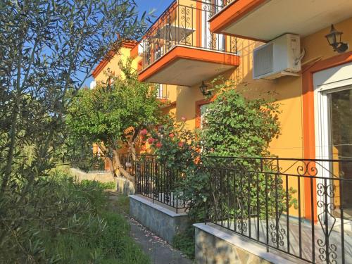 een geel gebouw met een balkon en planten bij Acapoulco apartments in Anaxos