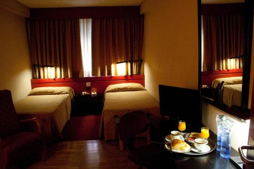 a hotel room with two beds and a table with food at Anaco in Madrid