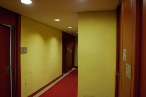 an empty hallway with yellow walls and red carpet at Anaco in Madrid