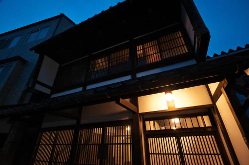 a building with a lit up window at night at Kanazawa Guest House East Mountain in Kanazawa