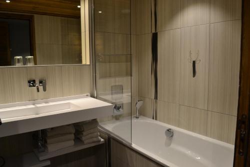 a bathroom with a tub and a sink and a bath tub at Hôtel Alpina & SPA - Restaurant Oxalis in Les Gets