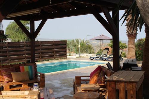 a swimming pool with a pavilion and chairs and a table at Zenovia Garden House in Pissouri