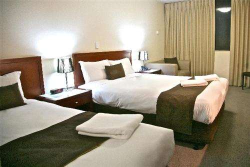 a hotel room with two beds with towels on them at City Park Hotel in Melbourne