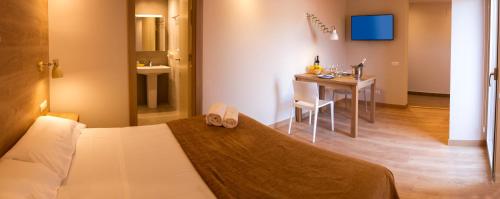 a hotel room with a bed and a table with a table at Apartamentos Voramar in Castelldefels