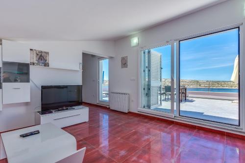 a living room with a tv and a large window at Apartments Host in Rab