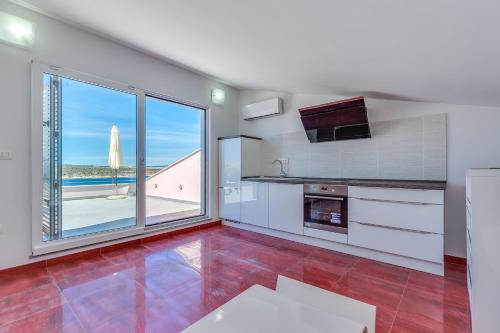 a kitchen with a large window and a view of the ocean at Apartments Host in Rab