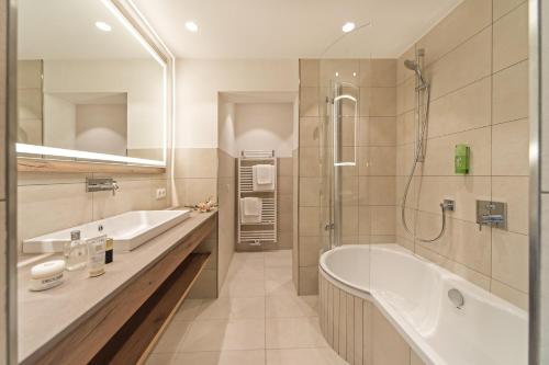 uma casa de banho com uma banheira, um chuveiro e um lavatório. em Sonnenhof Genusshotel & Appartements em Pertisau